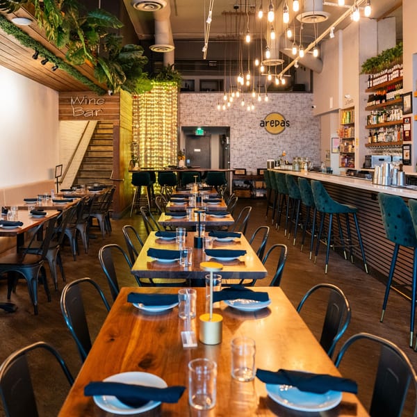 Interior of Arepas Latin Cuisine, featuring dining tables, a wine bar, and a fully stocked bar.