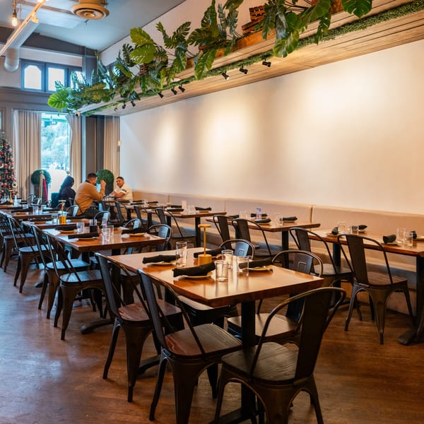 Arepas Latin Cuisine dining room with wooden tables, metal chairs, and plants hanging from the ceiling.