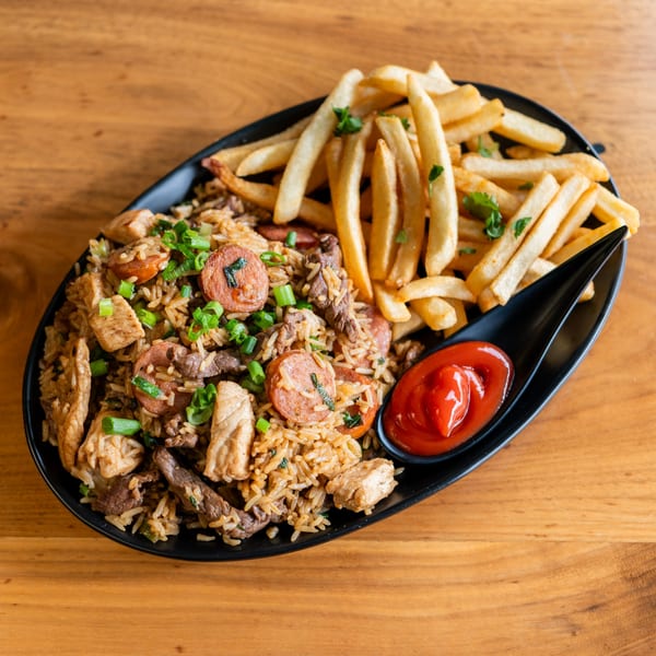 Venezuelan fried rice with chicken, beef, sausage, and french fries, served with ketchup.